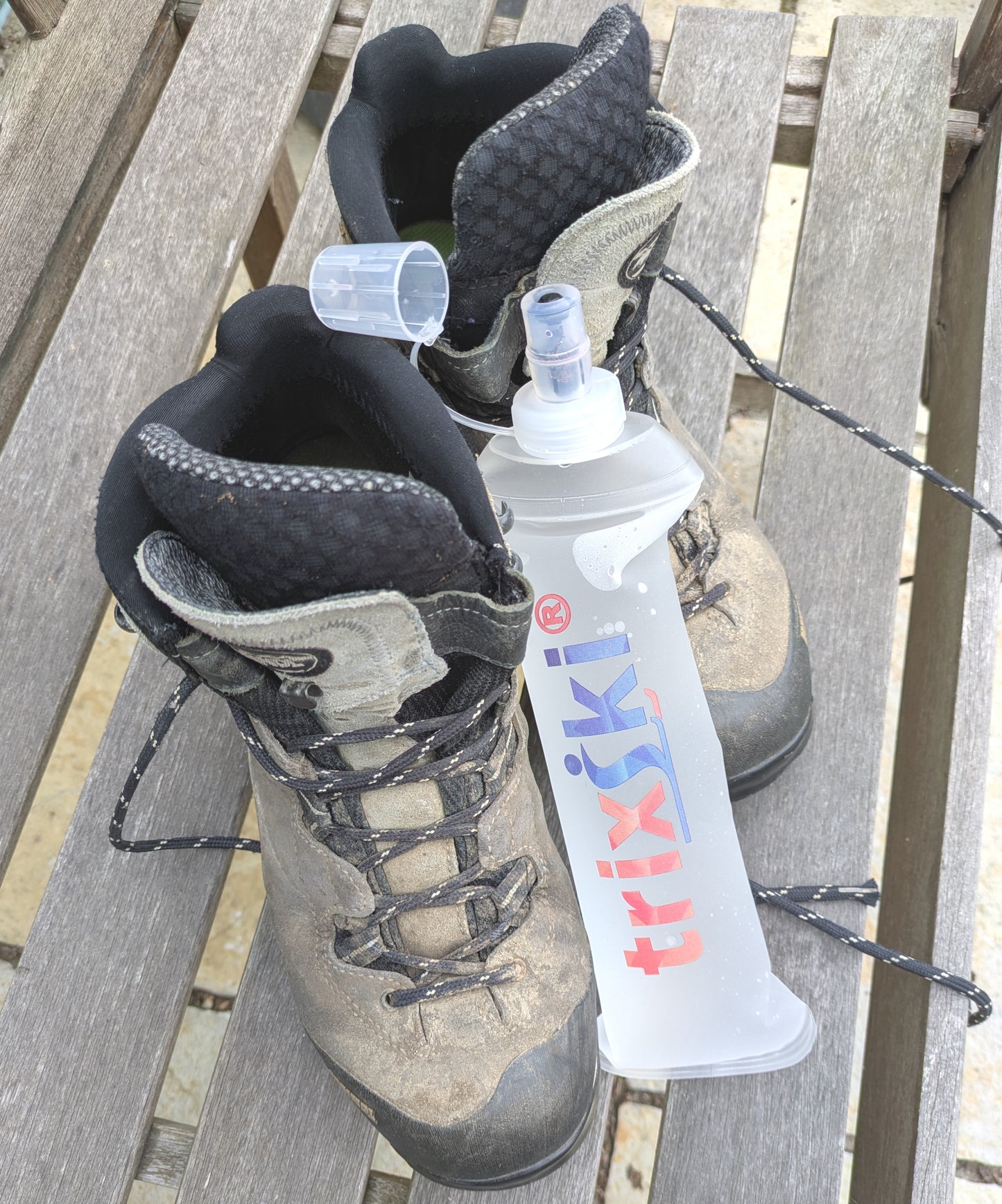 Pair of walking boots with a trixski bottle on a wooden seat