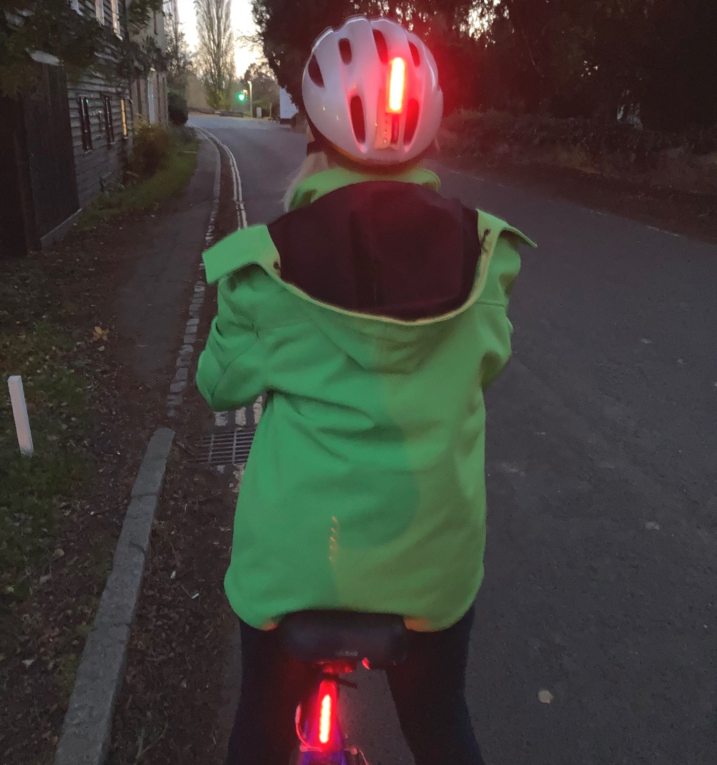 Rear view of a cyclist showing trixski LED Light in use on a cycling helmet and below the saddle