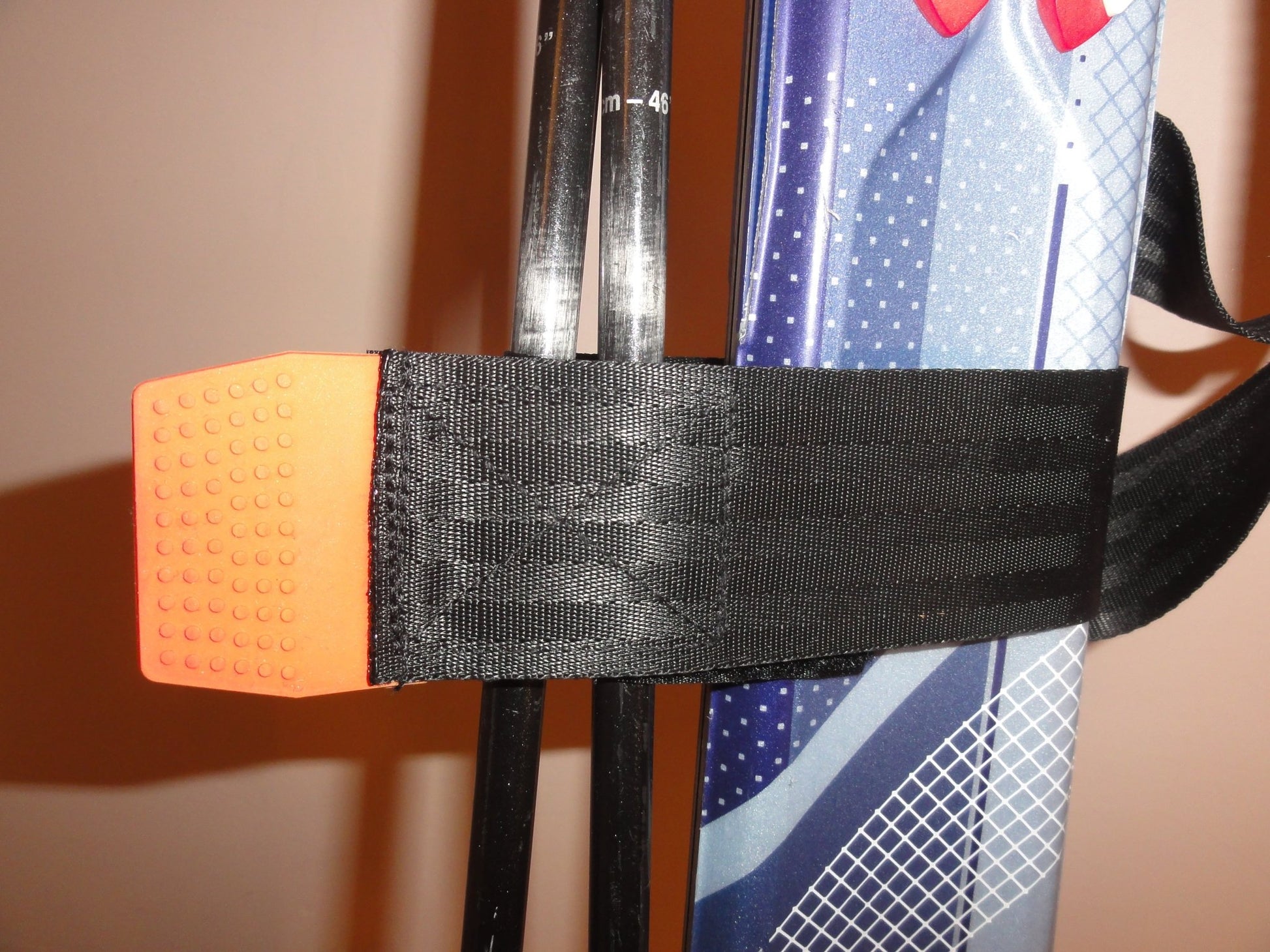 Close up of orange silicone puller tab on trixski Ski Carrier webbing strap
