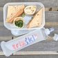 Picnic lunch container with sandwich and snacks, featuring a trixski silicone water bottle.