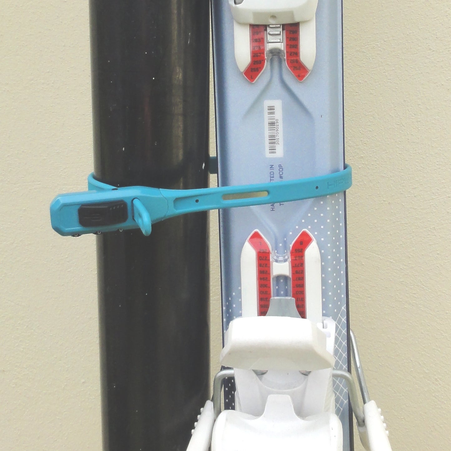 Skis held vertically to a fixed drainpipe by turquoise combination cable-tie style Z lock