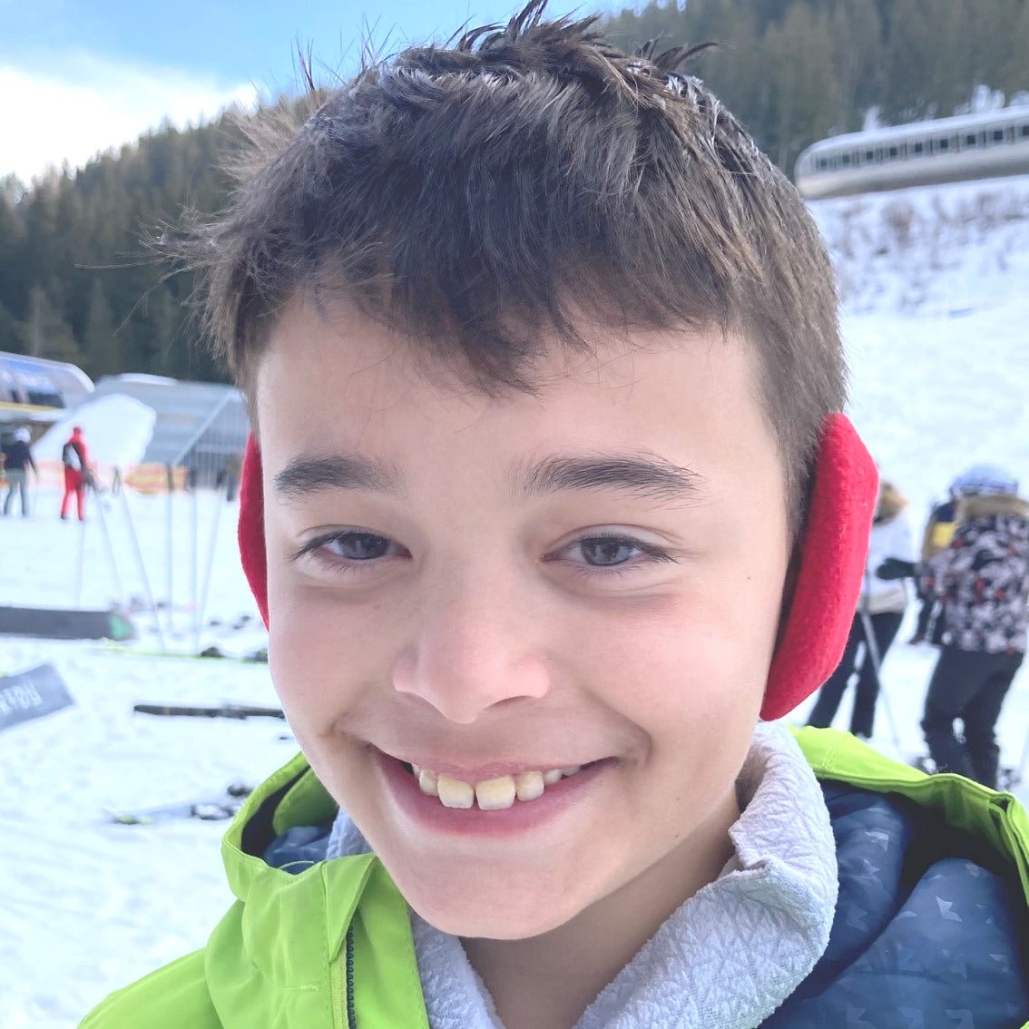 Young boy in ski location wearing red Snugga-Lugs